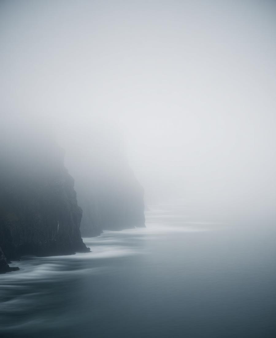 Misty coastal cliffs above still water at dawn
